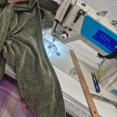 Green fabric being stitched on an industrial sewing machine
